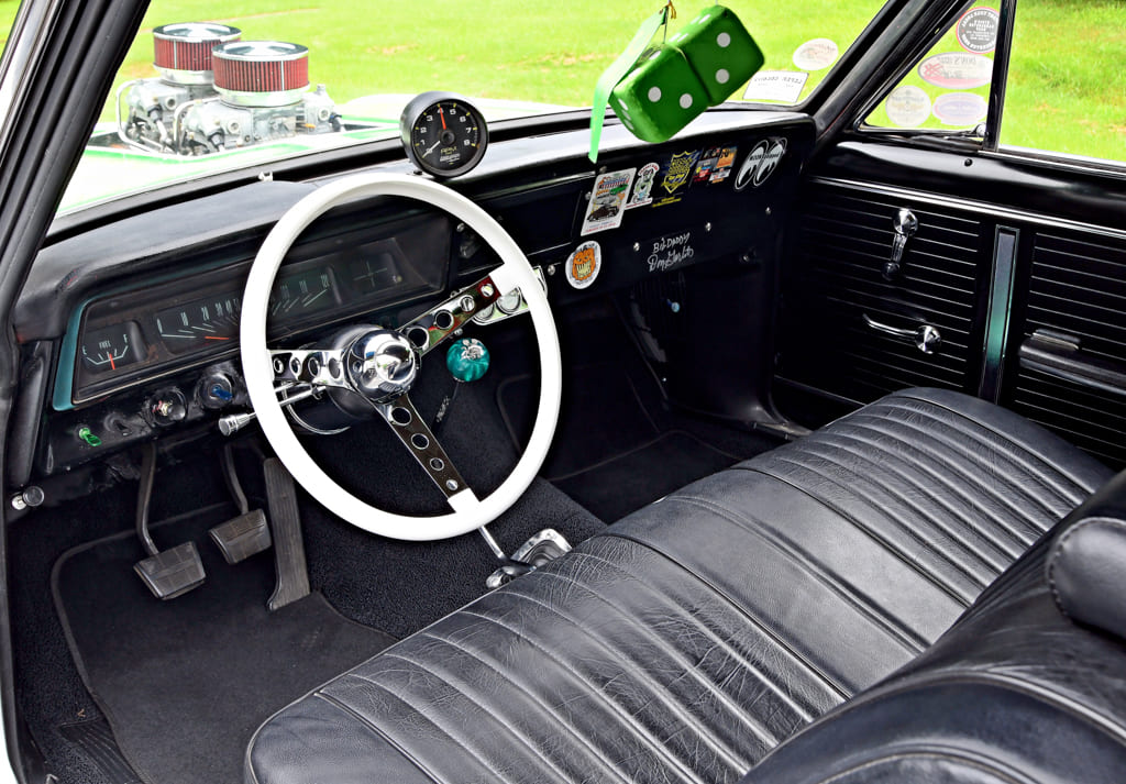 016 Interior of a 1966 Chevy Nova with a white steering wheel and fuzzy green dice 1966 chevy nova