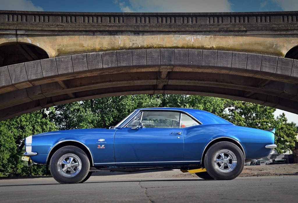 005 blue 1967 Camaro parked under a concrete bridge