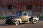 01 A matte two tone 1954 Chevy pickup with chrome wheels posed against a rustic barn backdrop